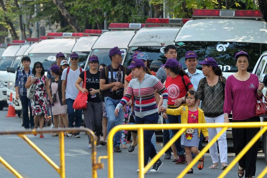 Tourists walks past police vans outside the parliament in Bangkok. Photo: AFP