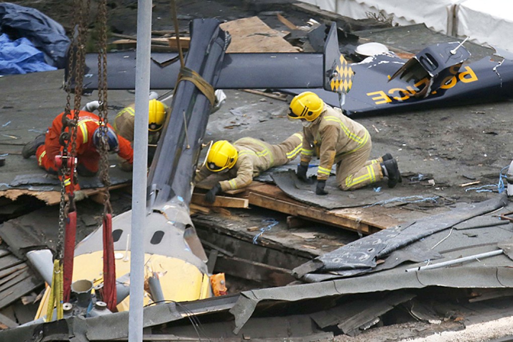 Rescue workers prepare to lift the wreckage of a police helicopter that crashed into a pub in central Glasgow, Scotland, on Monday. Photo: Reuters