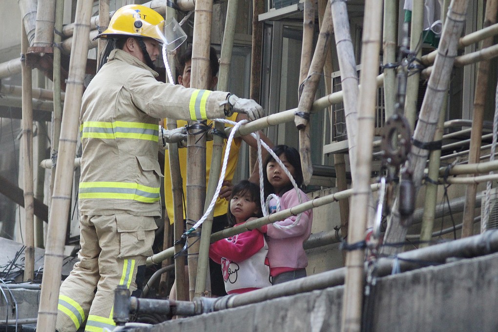 Two girls wait to be rescued after the fire in a first-floor subdivided flat. Photo: SCMP