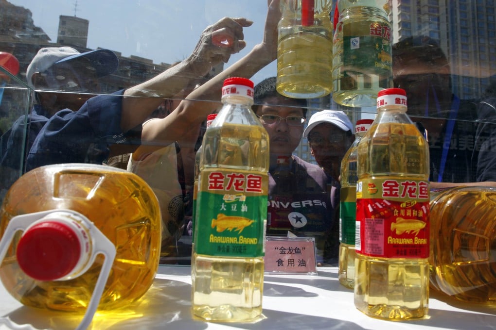 Consumers try to tell counterfeit cooking oil products from the real thing during an event to promote awareness of economic crimes in Beijing. Photo: AP