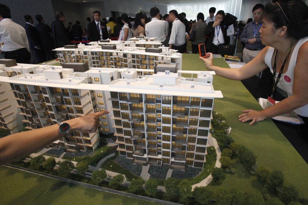 Prospective buyers look at a model of a condo development. Photo: Reuters