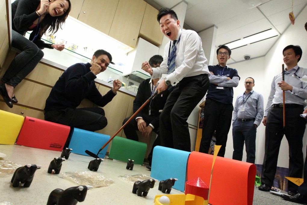 Colleagues cheer on Davy Yiu as he tackles a putt in the Bank of America Merrill Lynch Minigolf Day to raise money for Operation Santa Claus. Photo: Felix Wong