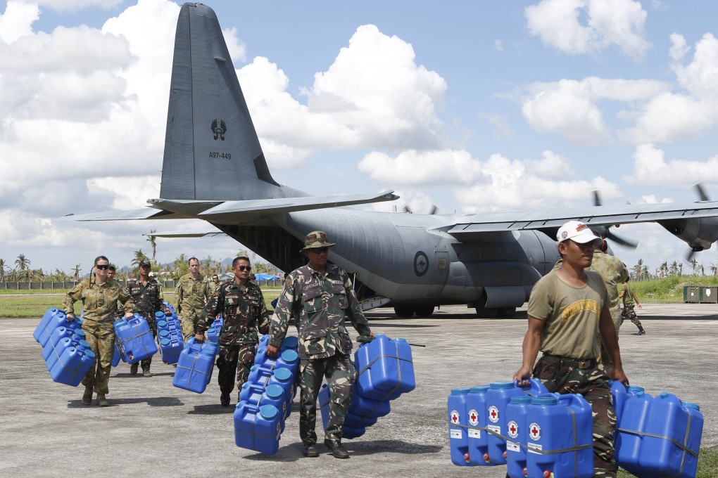 Australian and Filipino soldiers carry water containers for super Typhoon Haiyan survivors in Ormoc city in central Philippines. Photo: Reuters