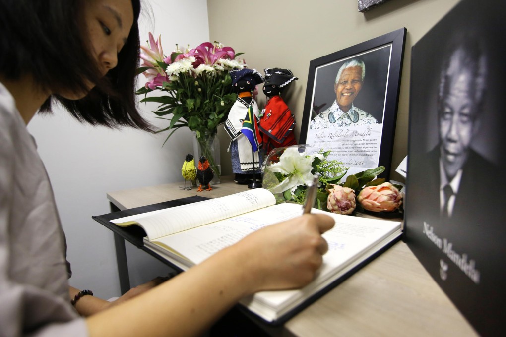 A Hong Kong woman signs the condolence book at the South African consulate amid pictures of Nelson Mandela. Photo: Sam Tsang