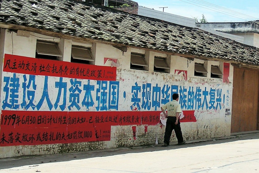 A man walks past a government propaganda banner on the one-child policy.