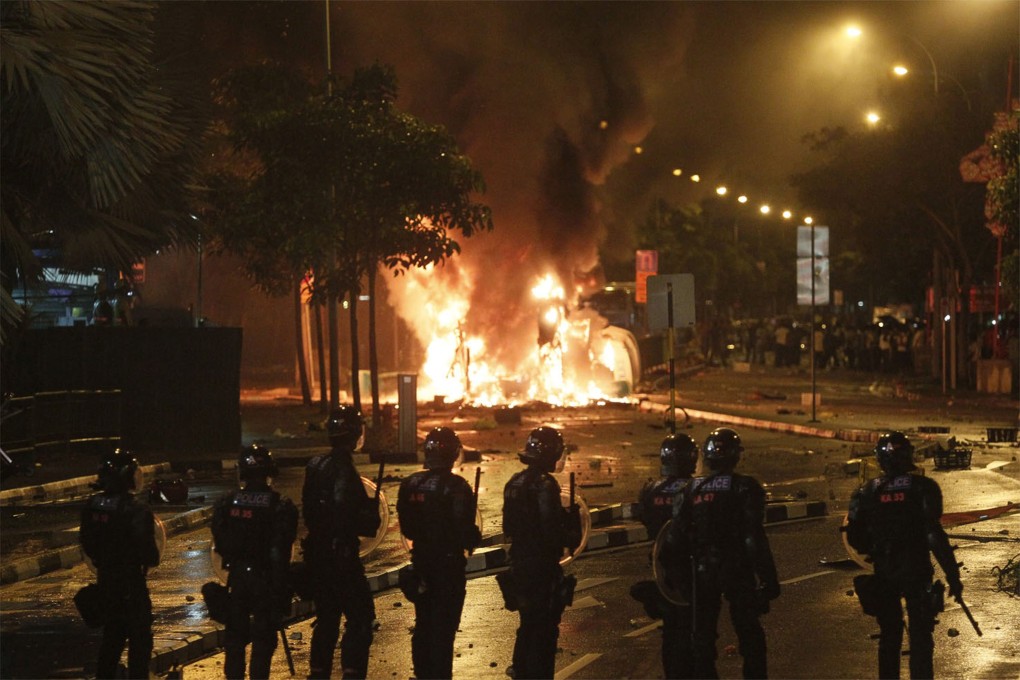 Riot police stand guard after a riot broke out in Little India. Photo: EPA