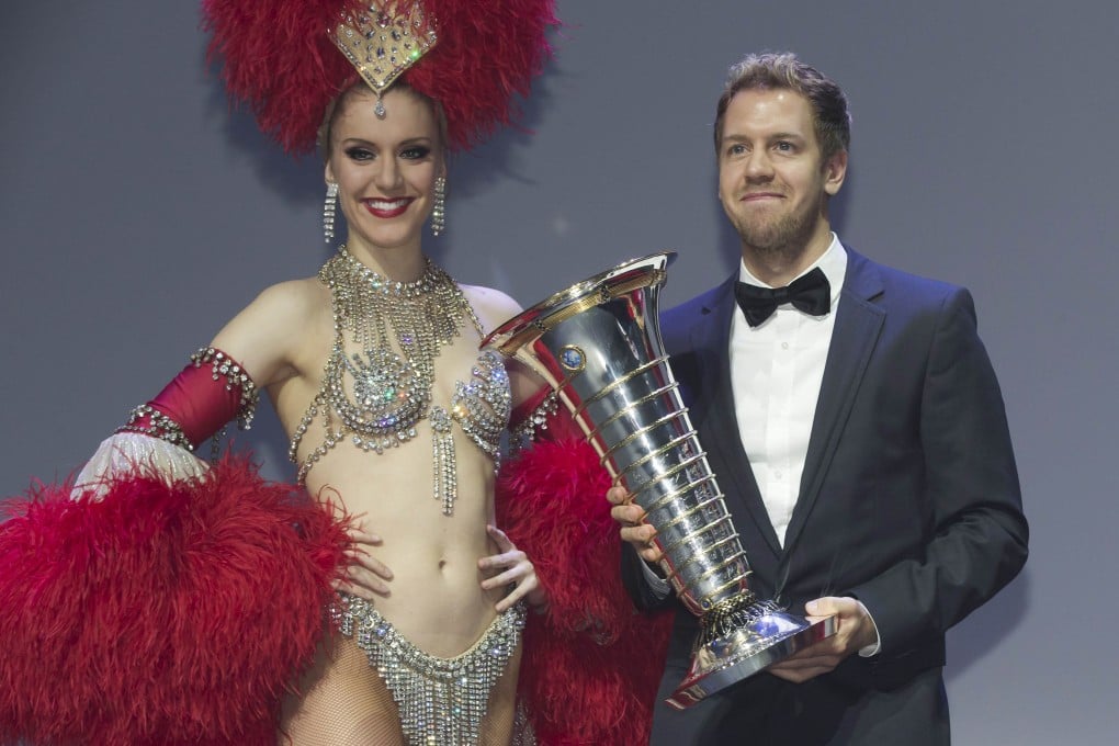 A Moulin Rouge dancer poses with 2013 Formula One World Champion Sebastian Vettel of Germany holding his trophy during the 2013 FIA prize-giving gala in Saint-Denis, outside Paris. Photo: AFP