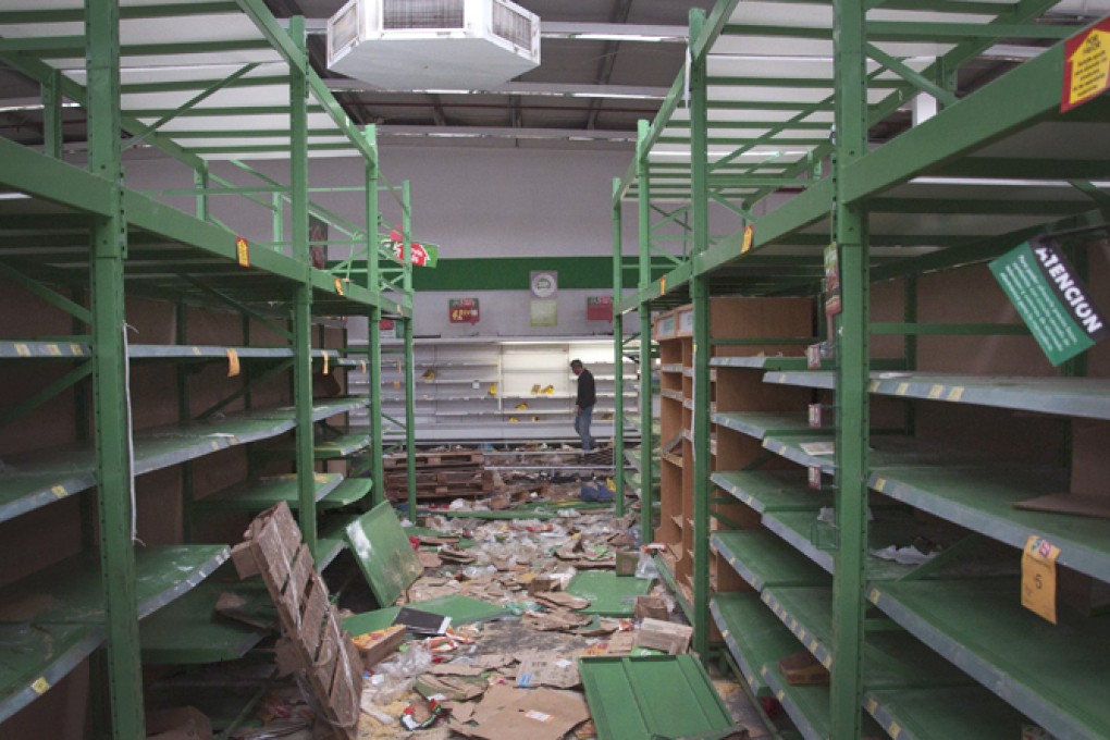 A shopkeeper inspects his store after it was looted in San Miguel de Tucuman, Argentina, Tuesday, Dec. 10, 2013. Photo: AP