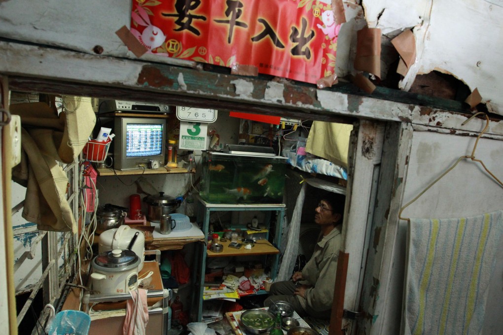 The modern face of poverty in Hong Kong. A man sits surrounded by his possessions in a cramped so-called cage home in Sham Shui Po. Photo: May Tse