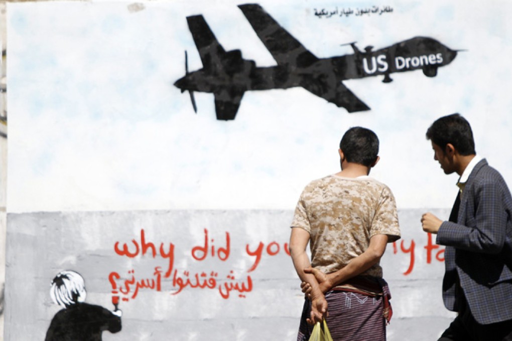 Men look at graffiti showing a US drone on a wall in Yemen. Photo: AFP