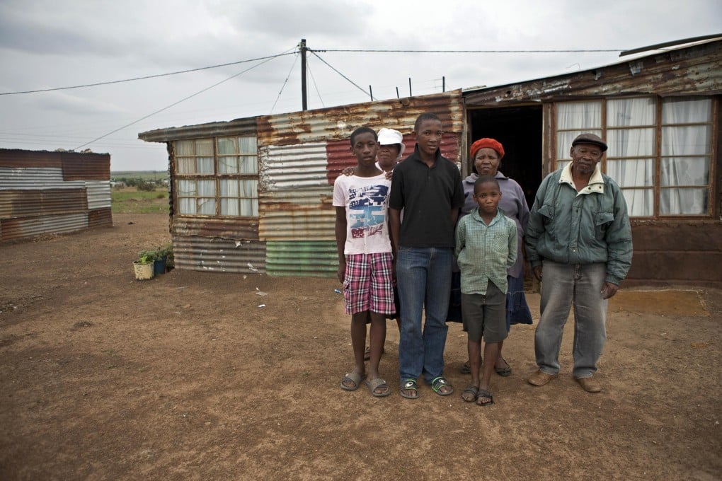 A formerly landless family stand outside their new home in Ventersdorp, South Africa. Photo: The Washington Post