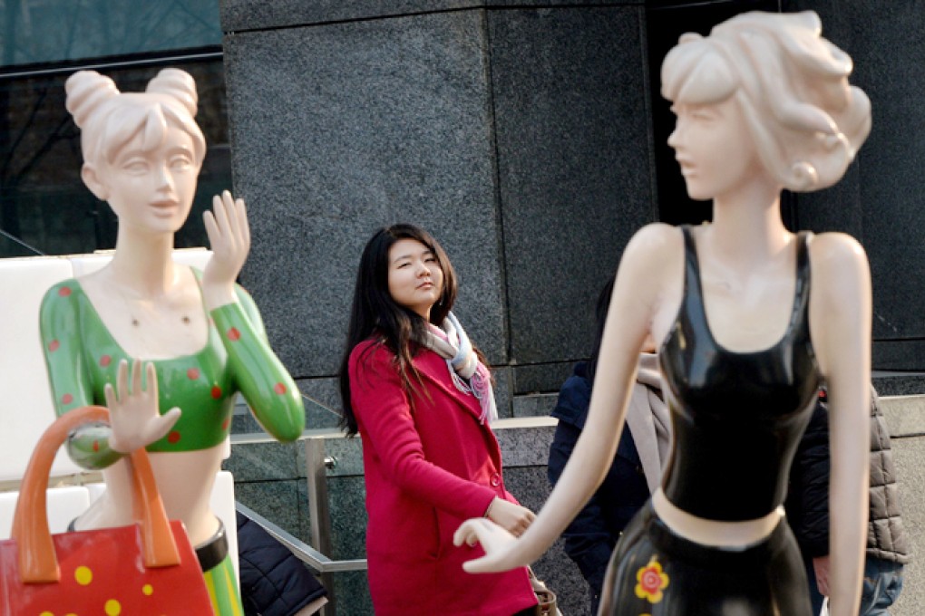 Chinese shoppers walk past mannequins outside a mall in Beijing. Retail sales grew at their strongest rate this year, suggesting the economy is on track to achieve the government's target of 7.5 per cent growth. Photo: AFP