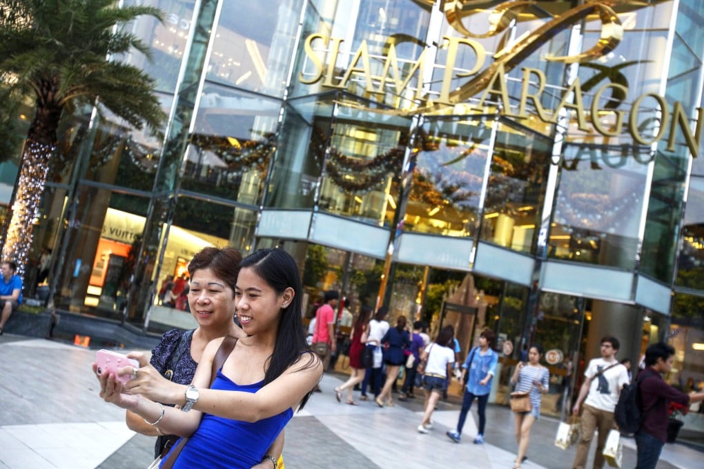 People take selfies in front of the Siam Paragon in Bangkok. Photo: Reuters