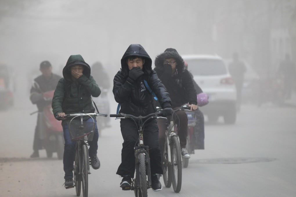 Residents cover their faces they ride their bicycles along a street on a smoggy day in Zhengzhou, Henan province. Photo: Reuters