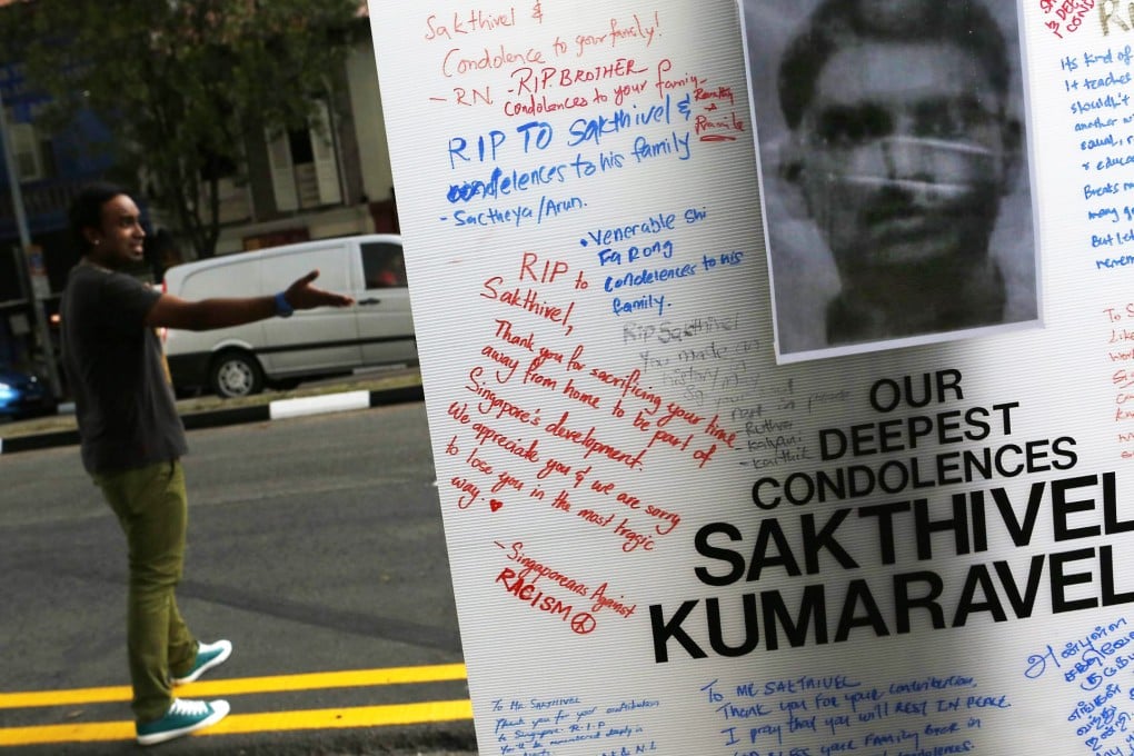 A man gestures behind a tribute board for Sakthivel Kumaravelu, an Indian national who was killed when he was struck by a bus, sparking a riot in the Little India district of Singapore. Photo: EPA