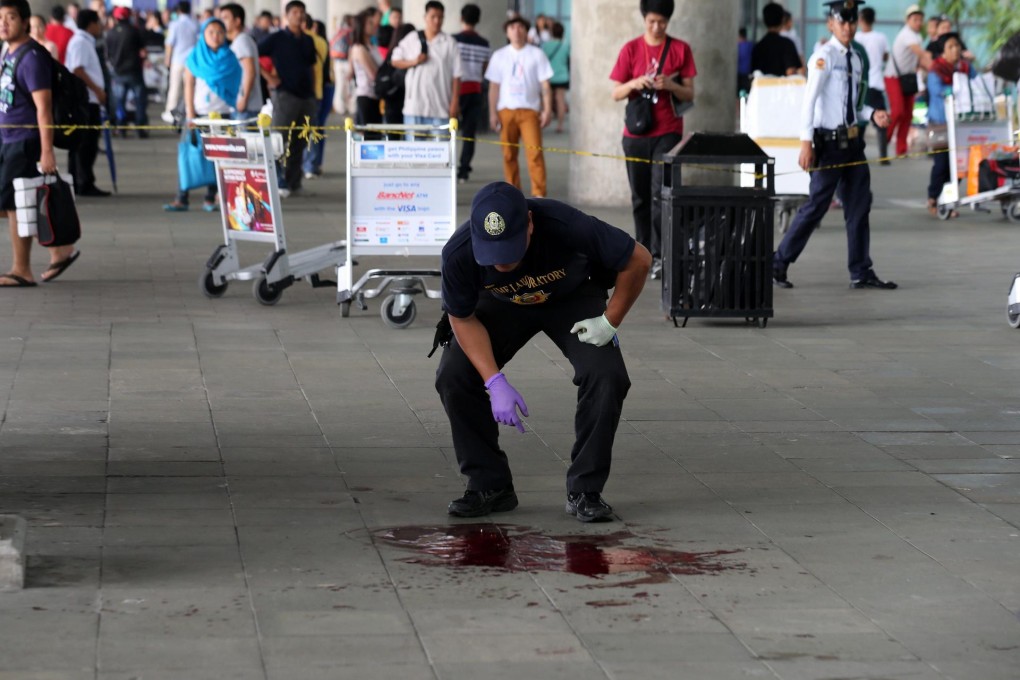 A police investigator examines a pool of blood at the scene of the shooting of mayor Ukol Talumpa and three others at Manila's international airport. Photo: EPA