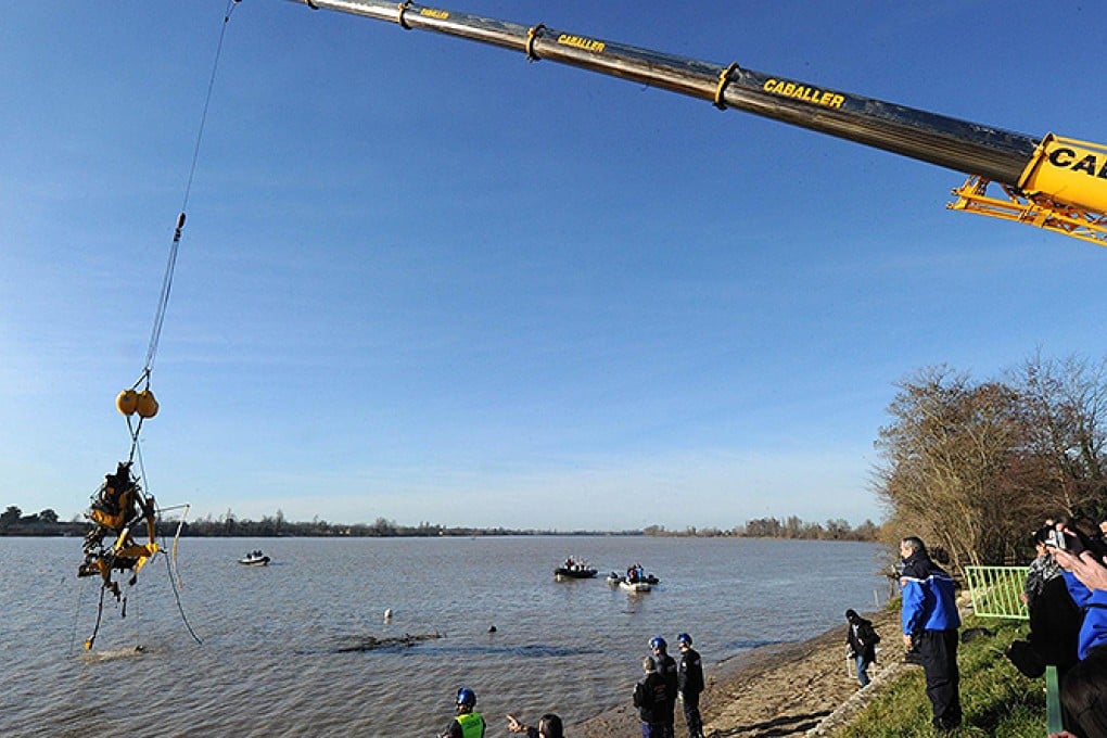 A crane lifts the wreckage of the helicopter out of the Dordogne river yesterday. Kok Lam, one of his sons, a French winemaker and an interpreter died in the crash. Photo: AFP