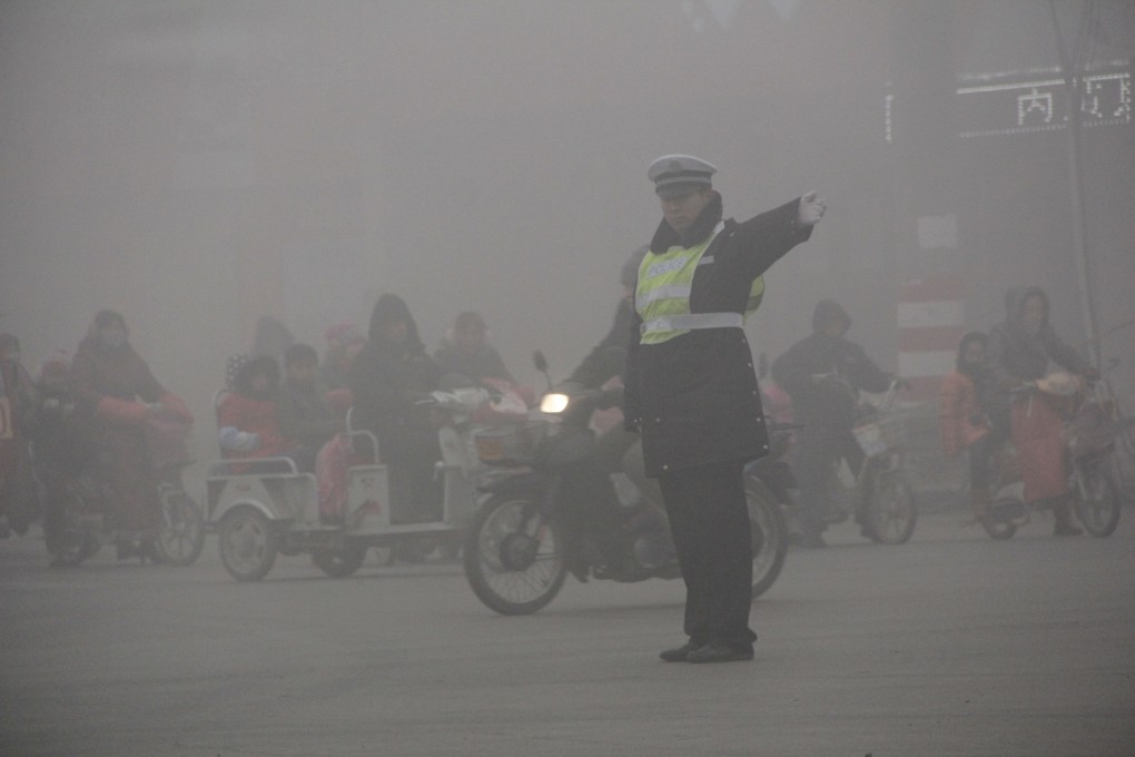 A policeman directing traffic in heavy smog in Anyang, Henan on December 20, 2013. Photo: CFP
