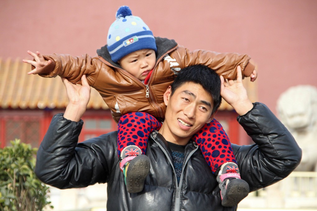 A Chinese man poses with his son as they visit Tiananmen Square in Beijing on December 5, 2013. Photo: AFP