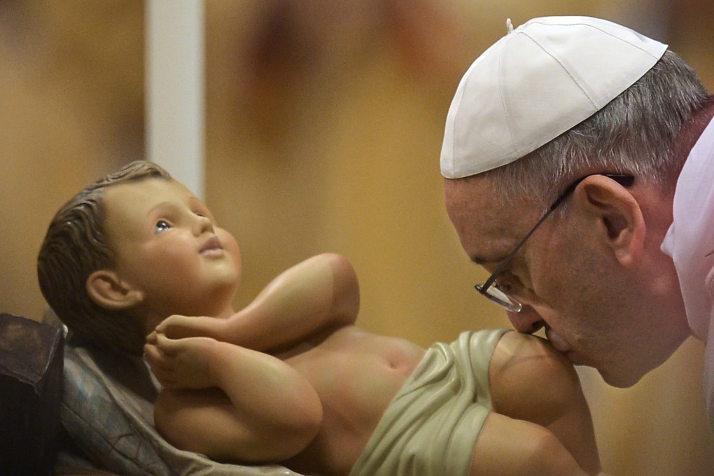 Pope Francis kisses the unveiled baby Jesus during a Christmas Eve mass at St Peter's Basilica to mark the nativity of Jesus Christ. Photo: AFP