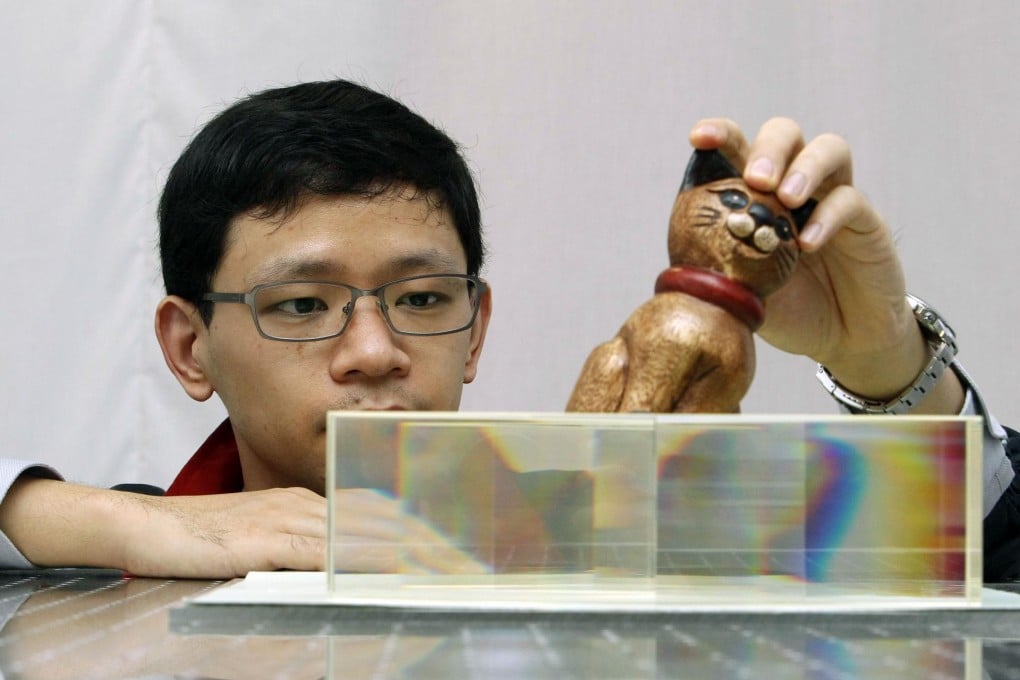 Nanyang Technological University researcher Zhang Baile uses glass blocks to show how an object may be made invisible. Photo: Reuters