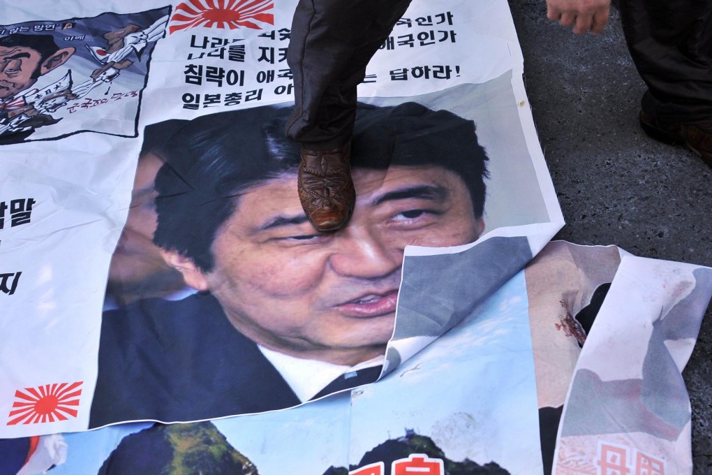 A protester stamps on a Shinzo Abe poster in Seoul. Photo: AFP