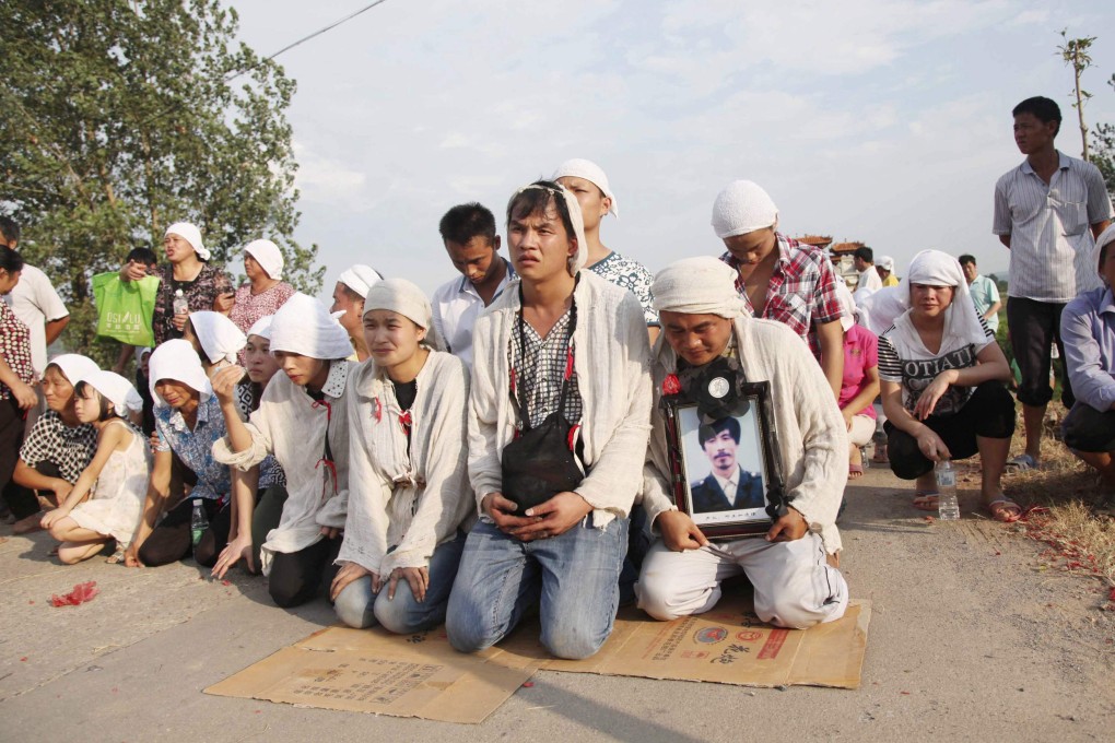 Grieving relatives hold a picture of 56-year-old farmer Deng Zhengjia at his funeral in July. Photo: Reuters
