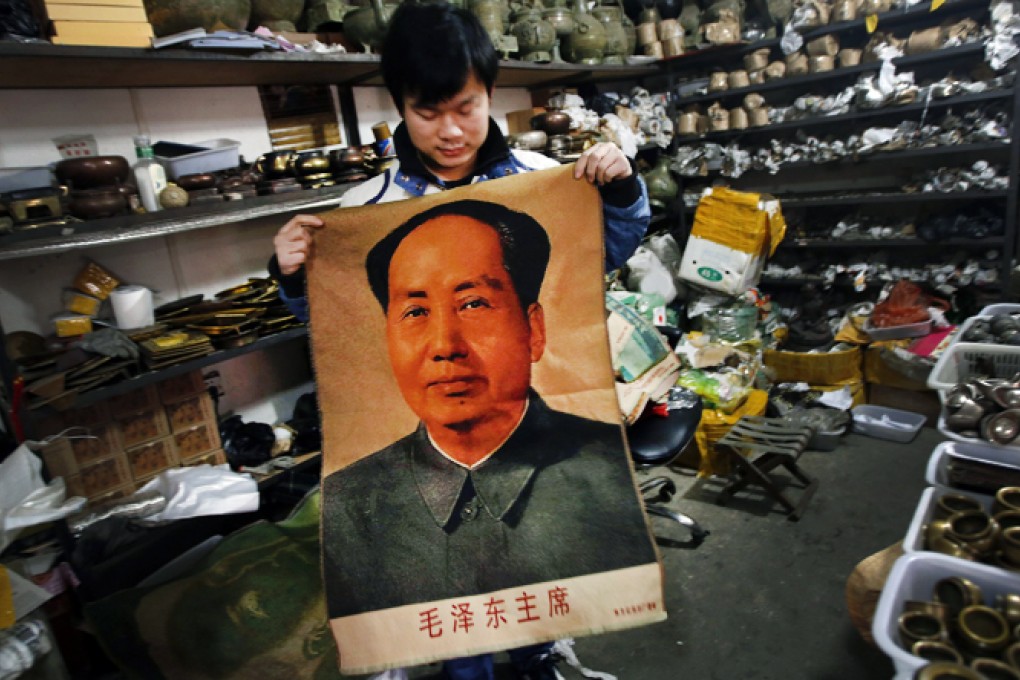 A clerk shows a wall hanging bearing the image of China's late Chairman Mao Zedong at an antique shop in Beijing. Photo: Reuters