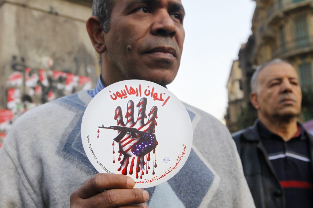 An Egyptian activist holds an anti-terrorism image with Arabic text that reads, "terrorists brotherhood". Photo: AP