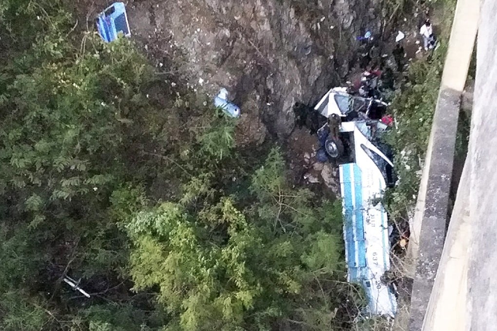 Emergency crews inspect the wreckage of the bus after it plunged into a ravine and (below) a rescue worker retrieves a body. Photo: EPA