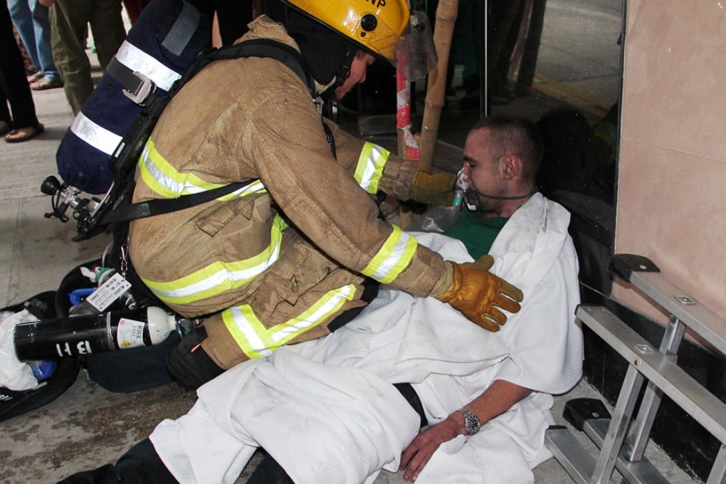 Emergency workers help a man overcome by smoke after a fire broke out at Continental Mansion in King's Road, North Point, yesterday. More than 20 people were injured, nine critically. It is believed scaffolding debris at the back of the property caught fire, before spreading to the apartment block and badly damaging a guesthouse. Photo: SCMP