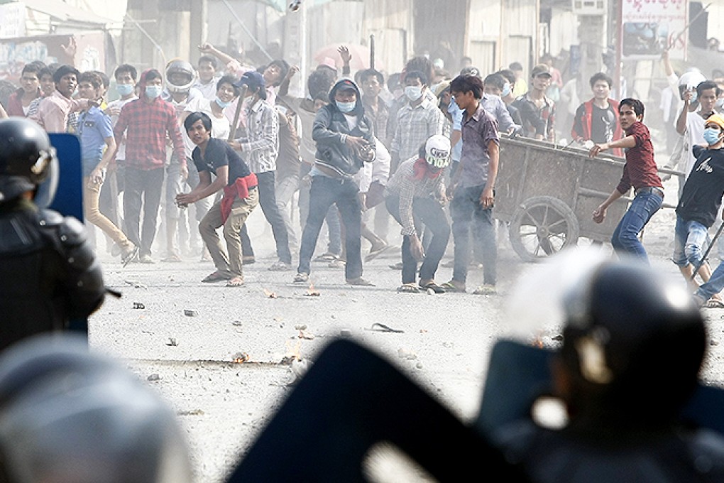 Garment workers are met with tear gas as they throw objects at riot police during a strike near a factory at the Stung Meanchey complex on the outskirts of Phnom Penh. Photo: AP