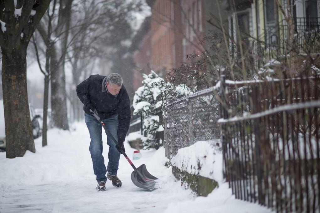 New York City Mayor Bill de Blasio clears the pavement of snow in front of his Brooklyn home in New York on Friday. Photo: Reuters
