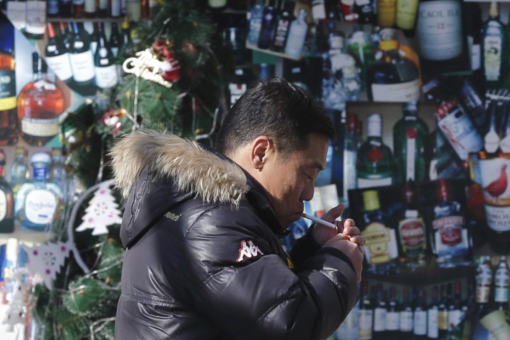 A Chinese man lights a cigarette while walking past a convenience store in Beijing. Photo: EPA