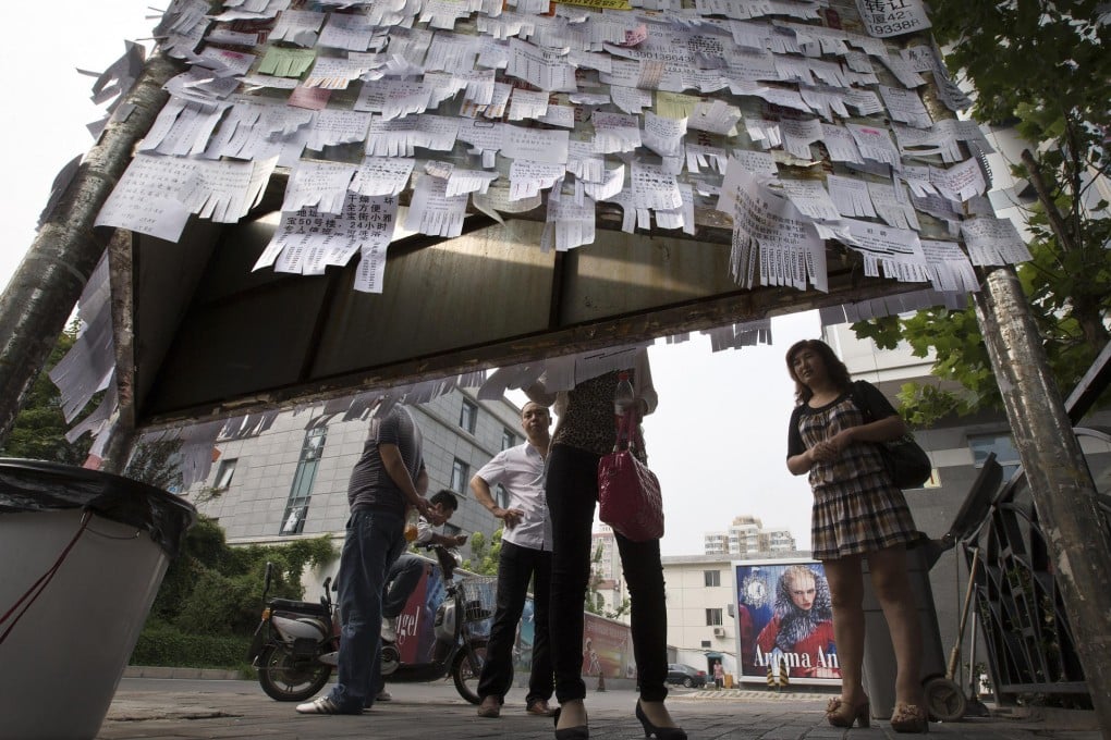 Pedestrians on a Beijing street check out adverts for rented rooms, flats or houses. Photo: Andy Wong