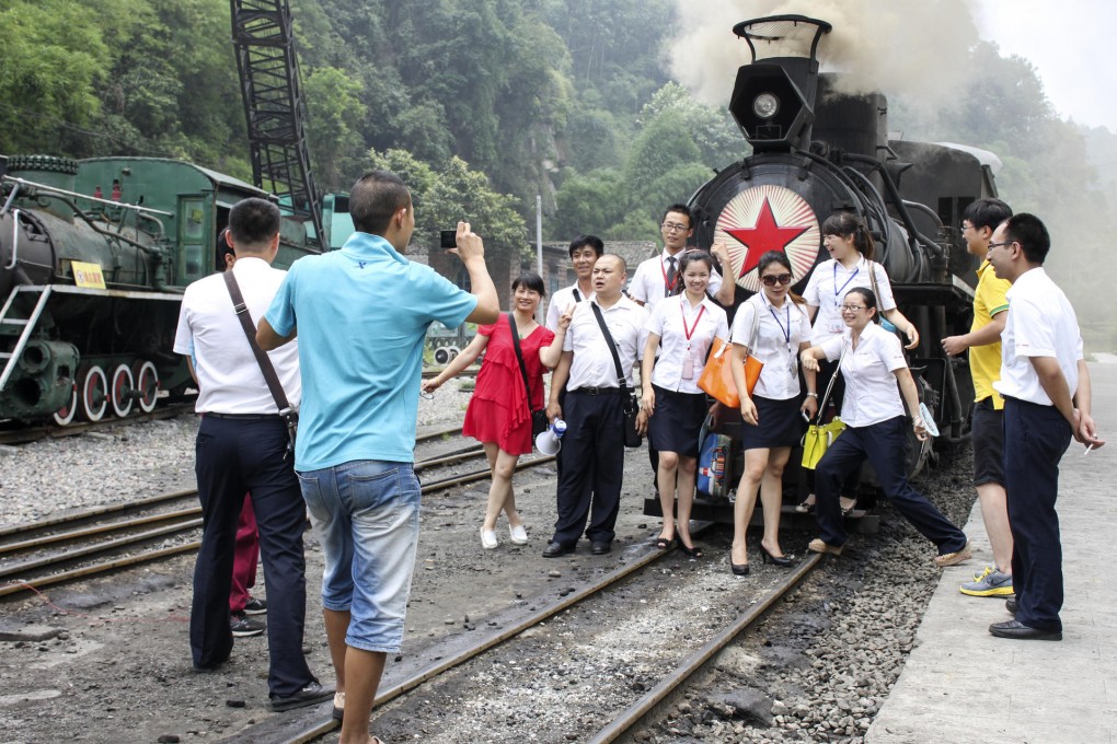 Visitors pose in front a steam engine on the Jiayang Railway line.