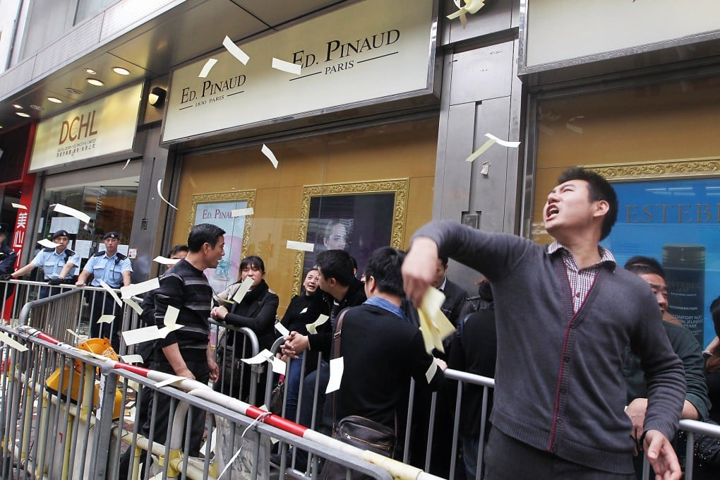 Angry mainland protesters throw hell notes and joss paper outside the DCHL sales centre in Canal Road West yesterday. Photo: Sam Tsang