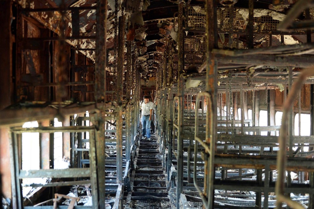 A rail official surveys a charred carriage outside Mumbai. Photo: AFP