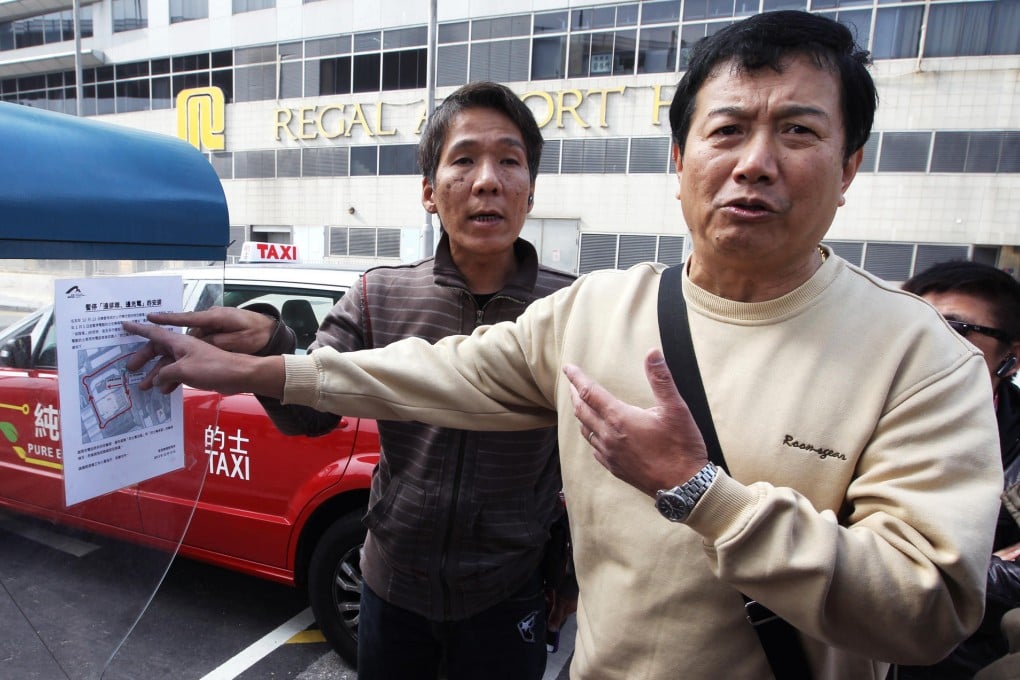 Drivers Chan Chi-hung (left) and Ng Yeuk-hon point at a notice that tells them to wait at the back of the queue. Photo: Edward Wong