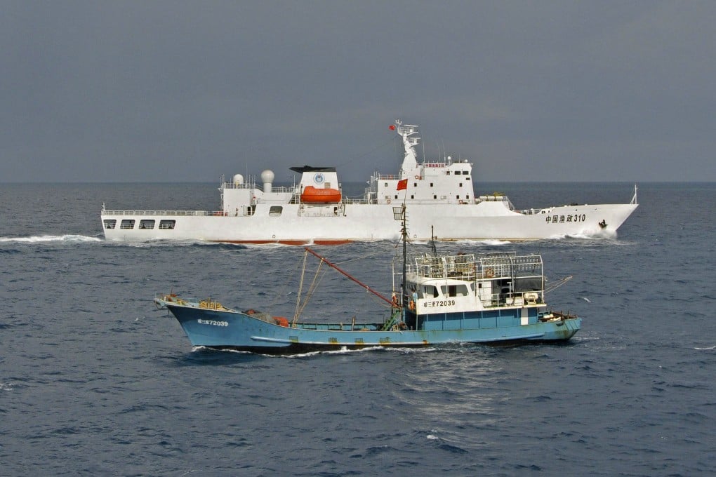 A Chinese fishery administration ship, background, guards a Chinese fishing vessel near Yongshu Reef of the Spratly islands in South China Sea, in 2012. Photo: Xinhua