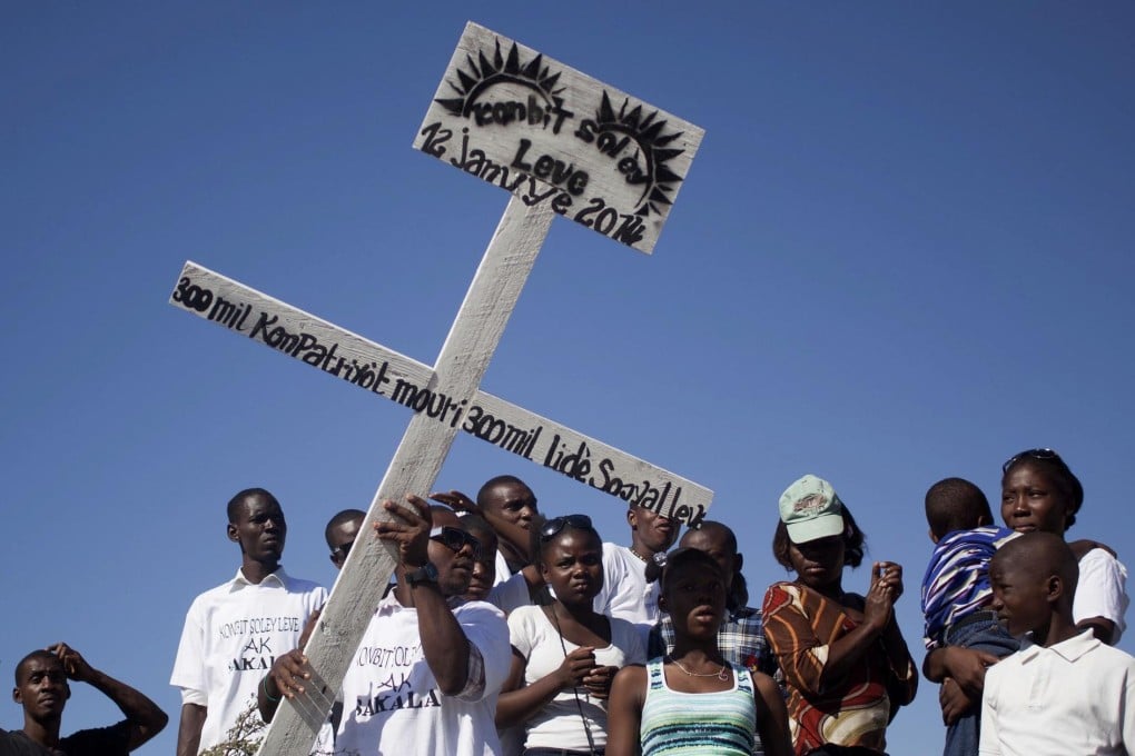 Haitians with a cross honouring relatives who were killed by the earthquake, along with a quarter of a million others. Photo: AP