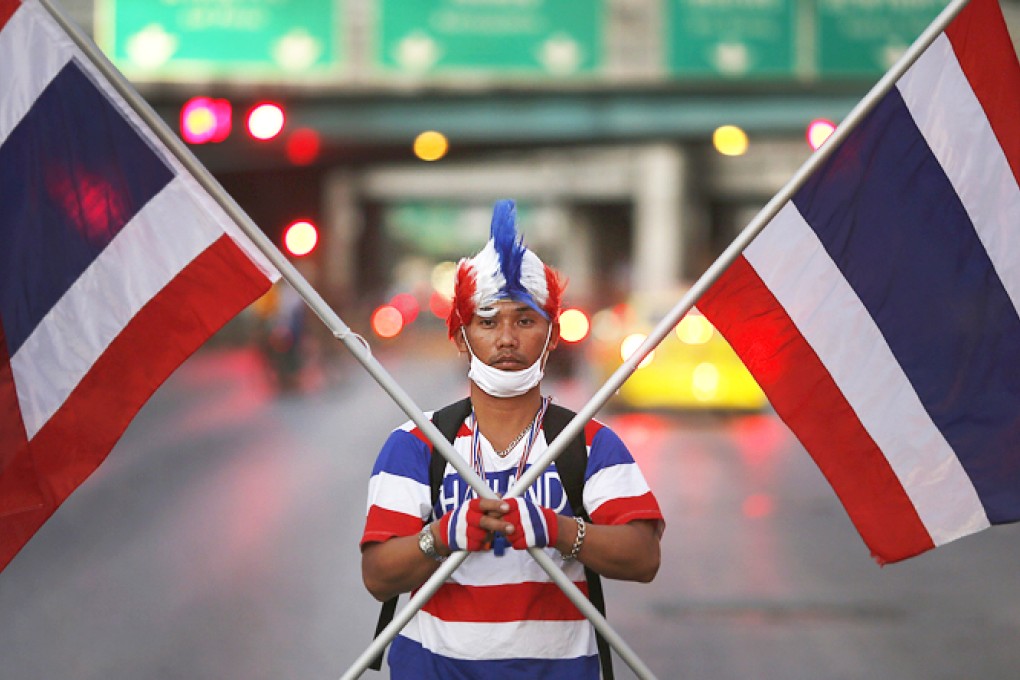 An anti-government protester holding national flags on Sunday arrives with a group to block one of city's the key intersections as a part of the shutdown. Photo: Reuters