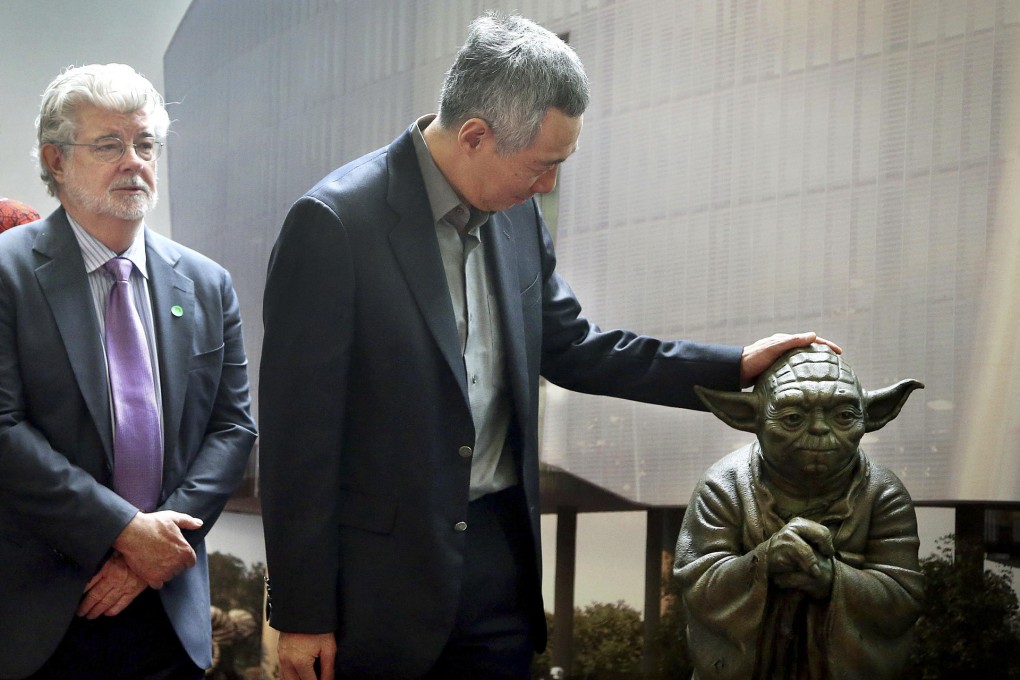 George Lucas watches as Lee Hsien Loong, Singapore's prime minister, admires a statue of Yoda at the opening of the "Sandcrawler" building. Photo: AP