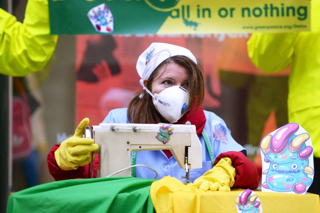 A Greenpeace activist in Budapest, Hungary, carries out a performance in a street protest on Tuesday in which she pretend to be sewing contaminated clothes with chemicals represented by little monsters. Photo: AFP