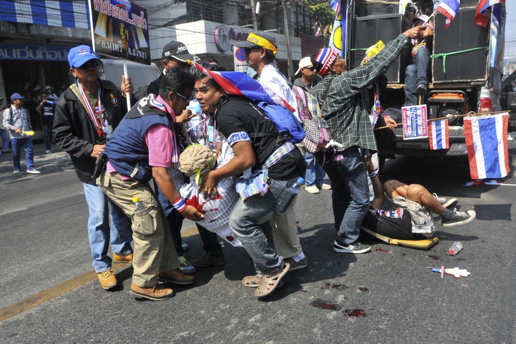 Thai protesters help the injured after an explosion during a rally in Bangkok on Friday. Photo: Reuters