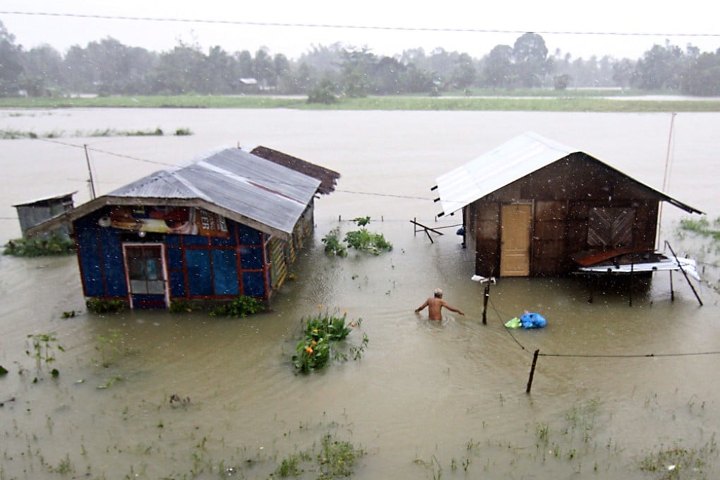 A resident wades through flood waters next to submerged houses after heavy rains at a village in Butuan. Photo: AFP