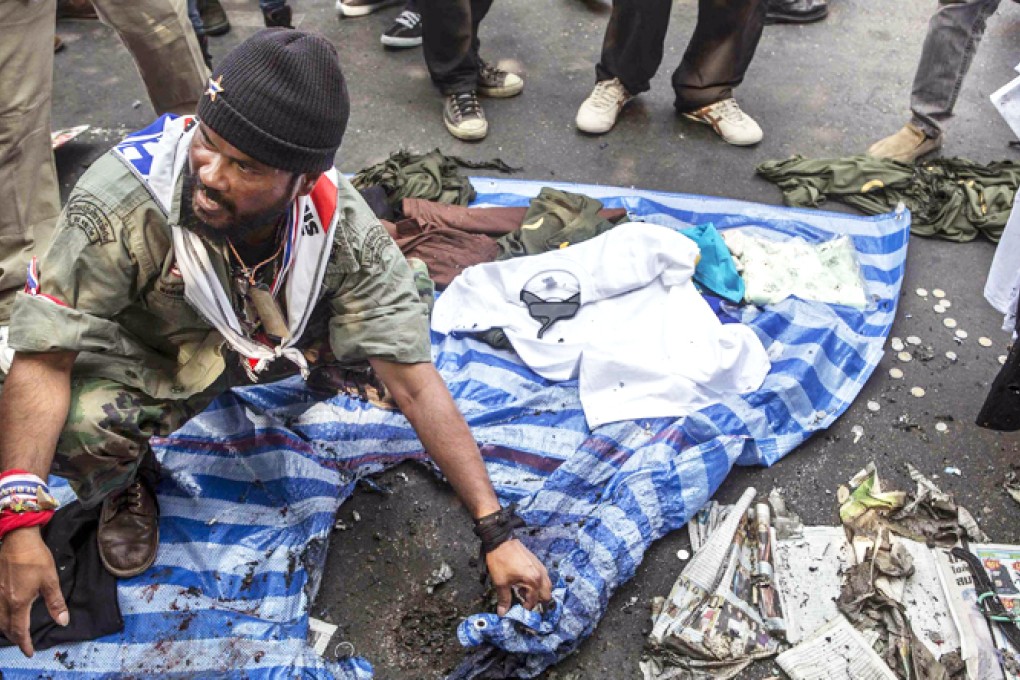 A protester at a rally site in Bangkok shows where an explosion took place. Seven people were seriously hurt in the attack. Photo: Reuters