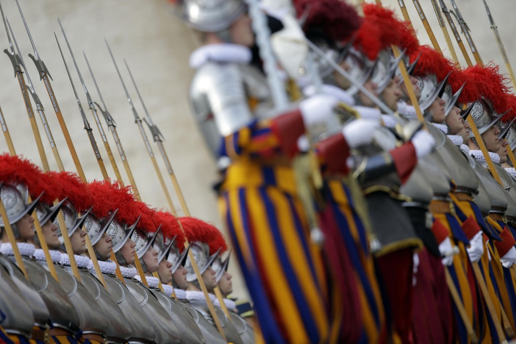 Swiss Guards, in their striking blue, red and orange uniforms, stand at attention at the Vatican. Photo: AP