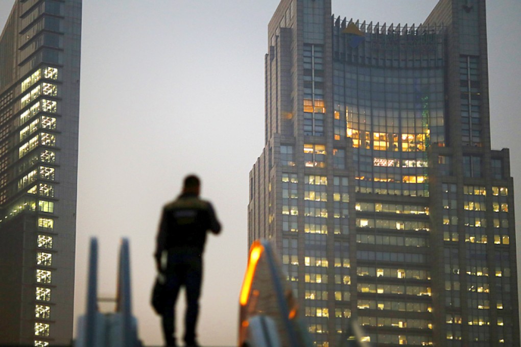 A man stands on an escalator in the financial district of Pudong in Shanghai in this November 20, 2013 file photo. Photo: Reuters