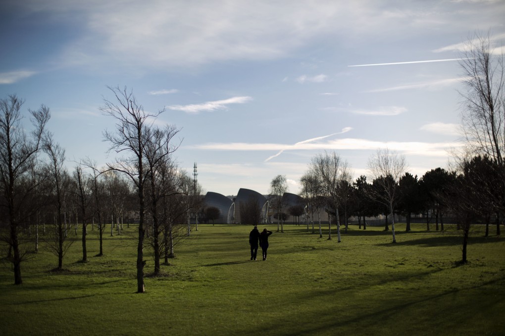 People walk in a park towards the Thames Barrier as it stands open on the River Thames in east London. Photo: AP